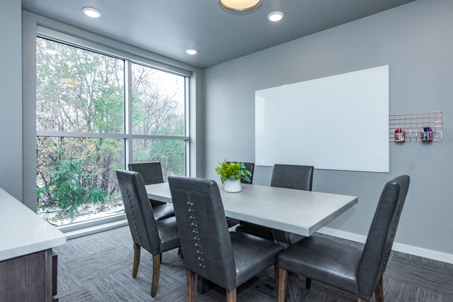 A conference room with a white table and grey chairs.