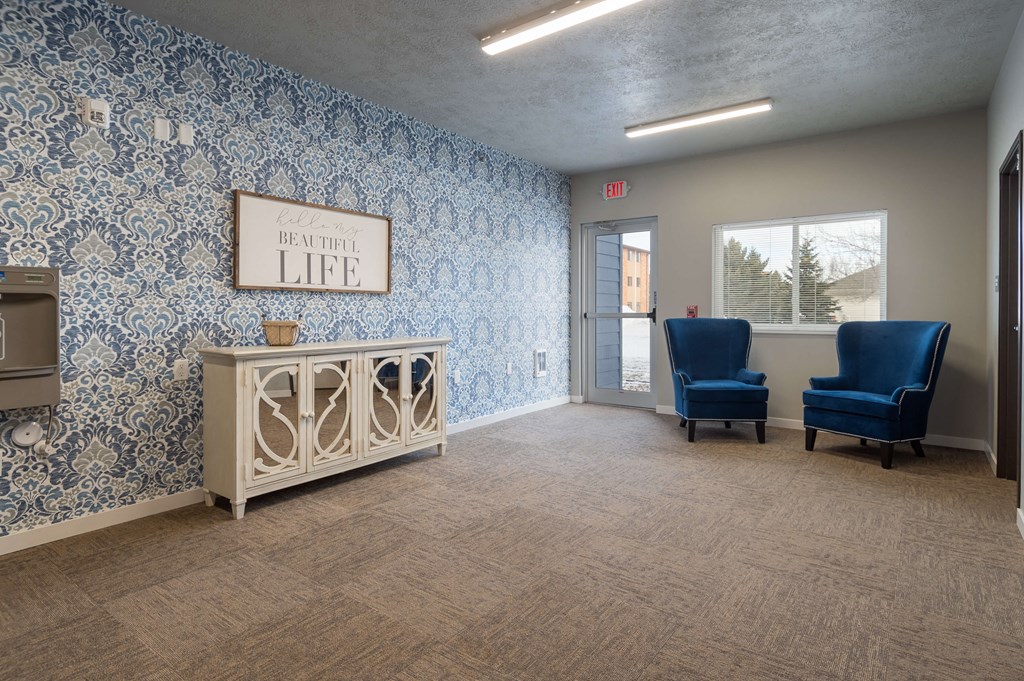 a waiting room with blue chairs and a white cabinet and a window