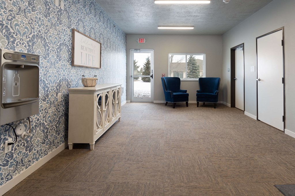 a large hallway with blue chairs and a washing machine and a door