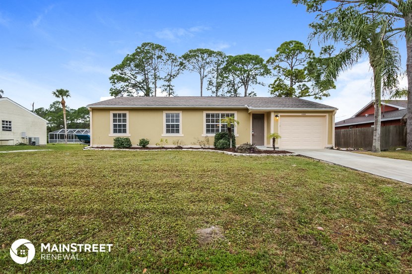 a yellow house with a lawn and palm trees