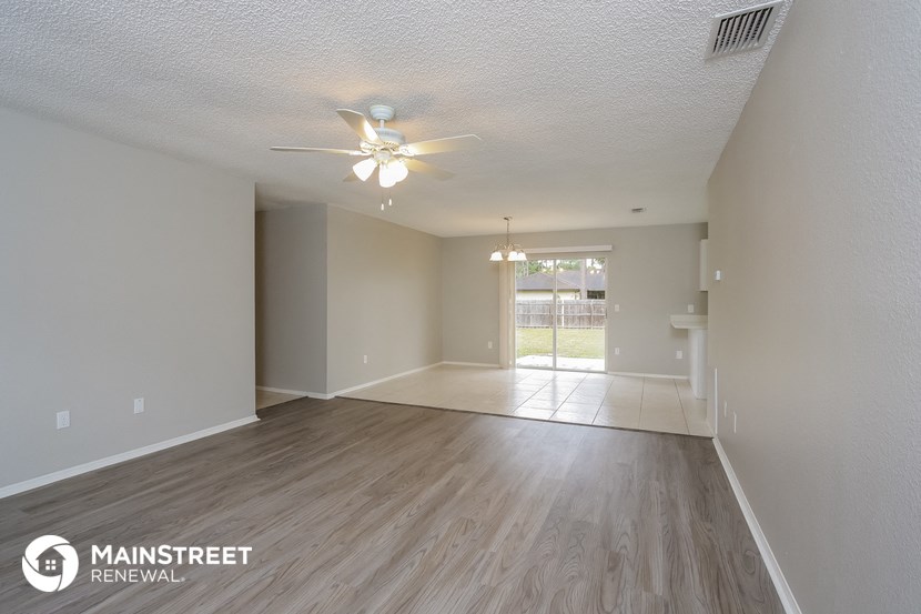 the spacious living room with ceiling fan and wood flooring