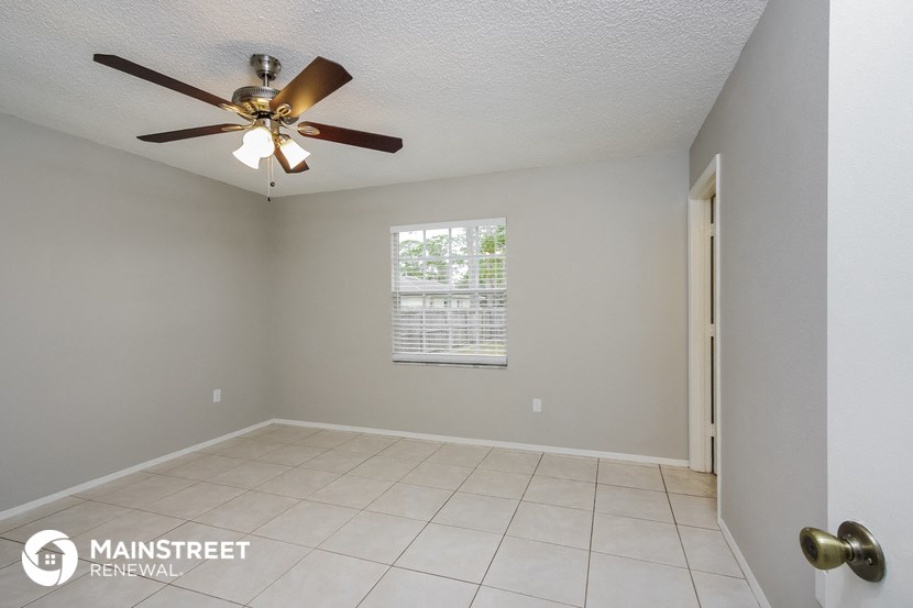 the living room has a ceiling fan and a tiled floor