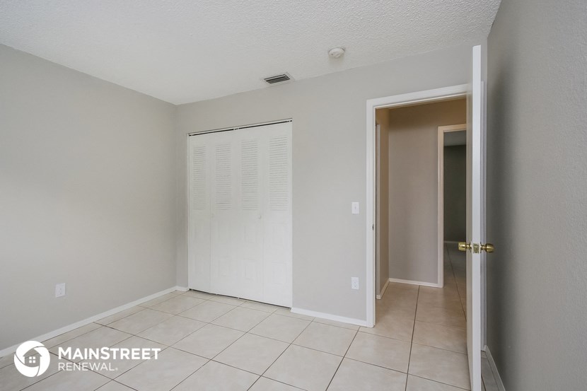 an empty hallway with a door to a closet and a tiled floor