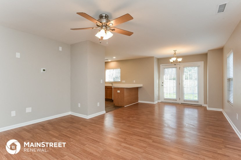 the living room and dining room with wood floors and a ceiling fan