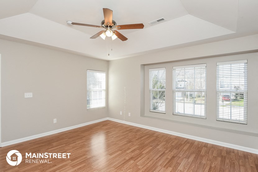 the living room of a new home with wood flooring and a ceiling fan