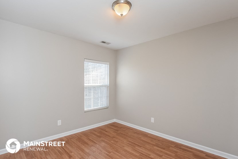 the spacious living room with hardwood flooring and a window