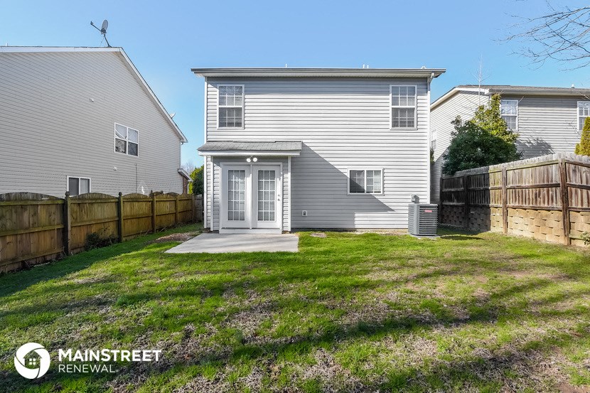 a backyard with a white house and a wooden fence