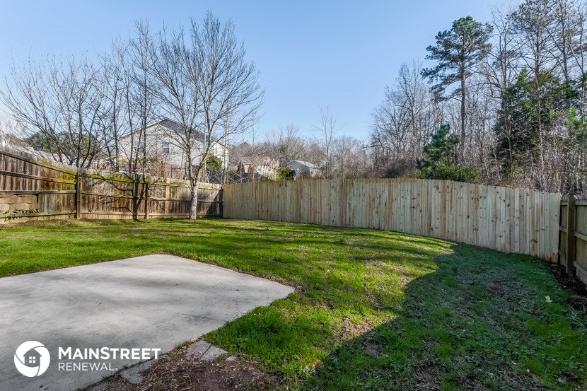 a backyard with a wooden fence and a yard with green grass