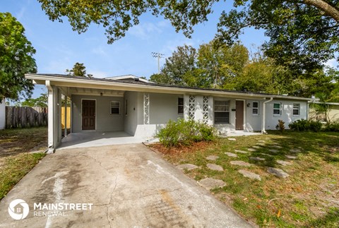 the front of a white house with a driveway and trees