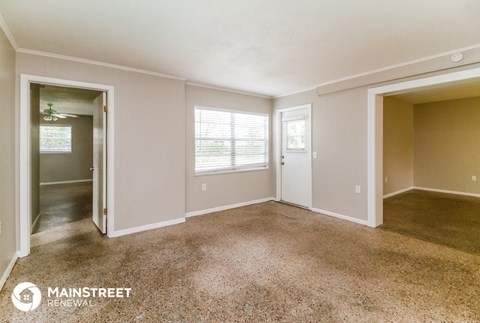 an empty living room with a door to a hallway and a window