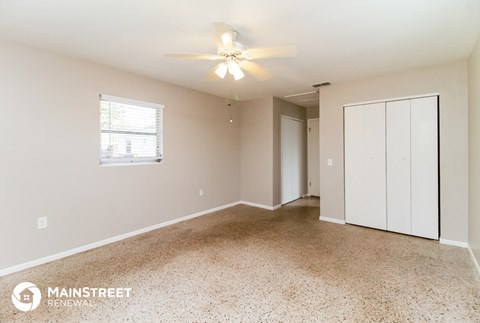 the spacious living room with white cabinets and a ceiling fan