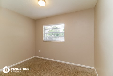 the spacious living room has carpeted floors and a window