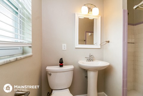 a bathroom with a toilet sink and a mirror and a window