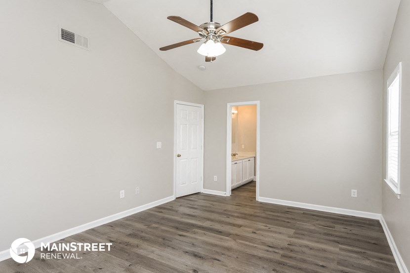 the spacious living room with wood flooring and a ceiling fan