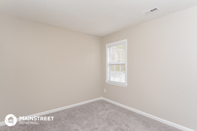 a bedroom with a carpeted floor and a window