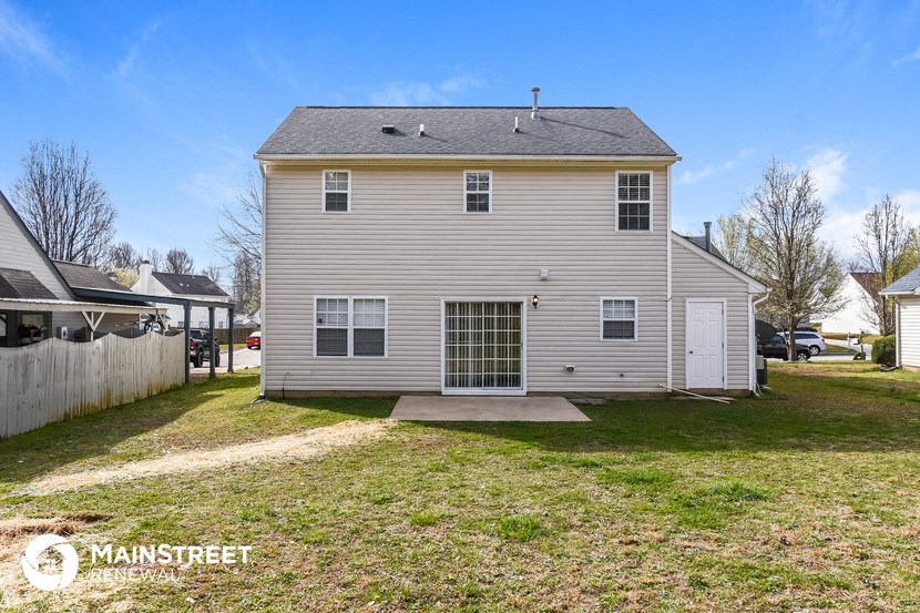 the back of a white house with a yard and a white fence