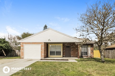 the front of a brick house with a yard and a sidewalk