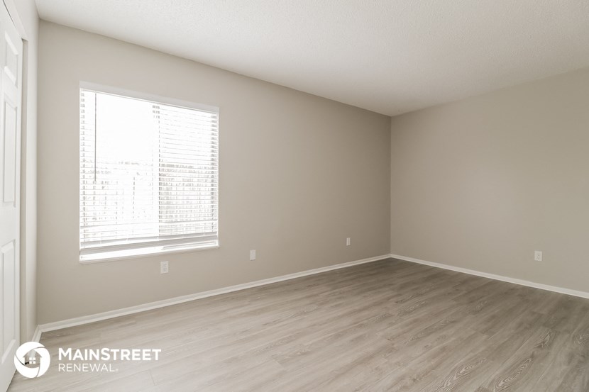the spacious living room with wood flooring and a large window