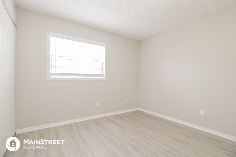 the upstairs bedroom with wood floors and a window