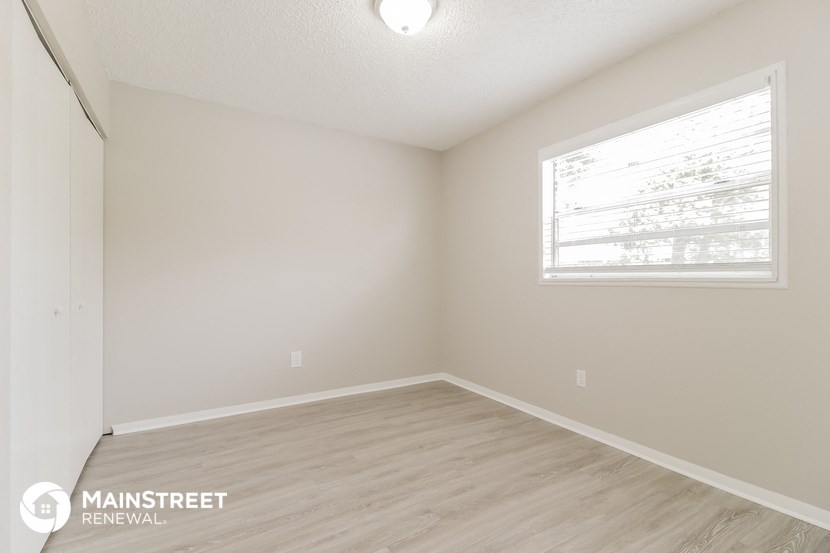 the spacious living room with wood flooring and a large window