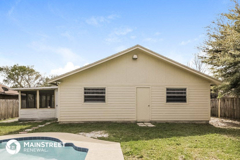 the front of a white house with a yard and a pool