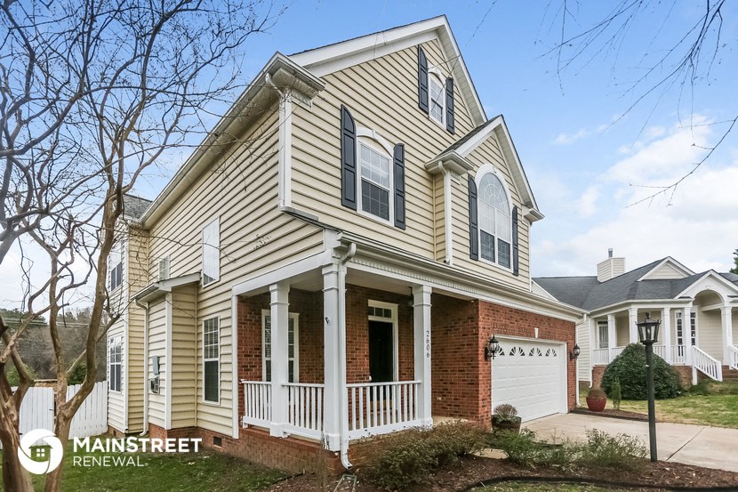 a yellow house with a white porch and a white garage door