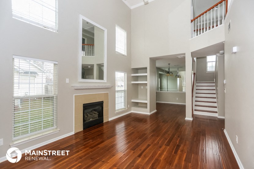 a living room with a hardwood floor and a fireplace   and a staircase