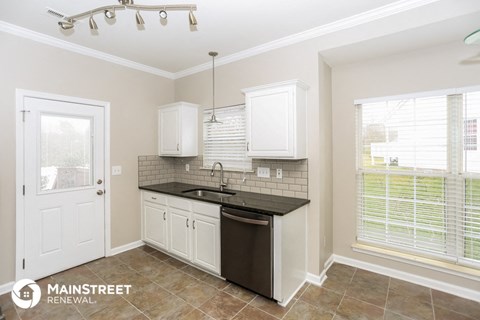 a kitchen with white cabinets and a black counter top