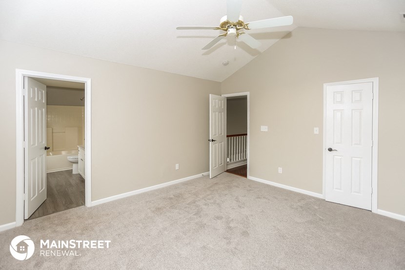 a living room with a ceiling fan and a carpeted floor