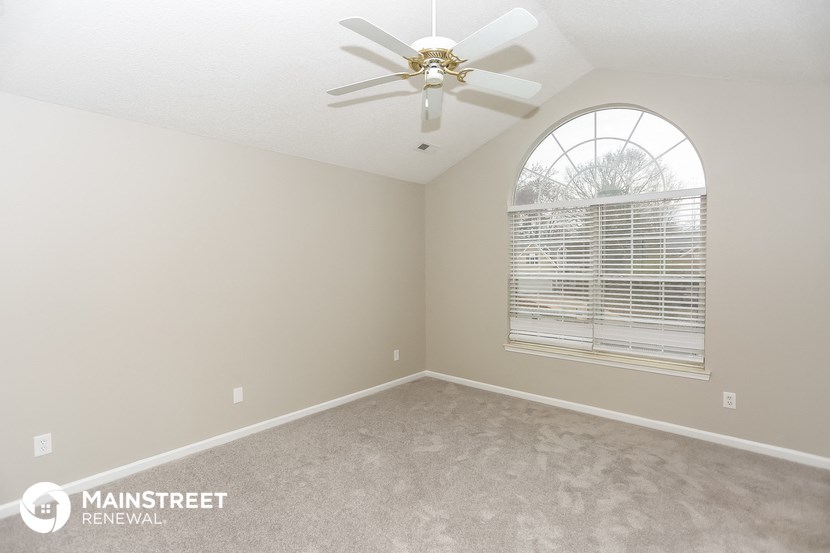 the master bedroom has a ceiling fan and a large window