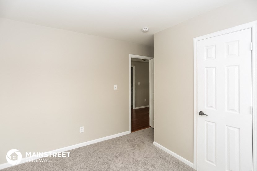 a bedroom with a white door and a hallway to a closet