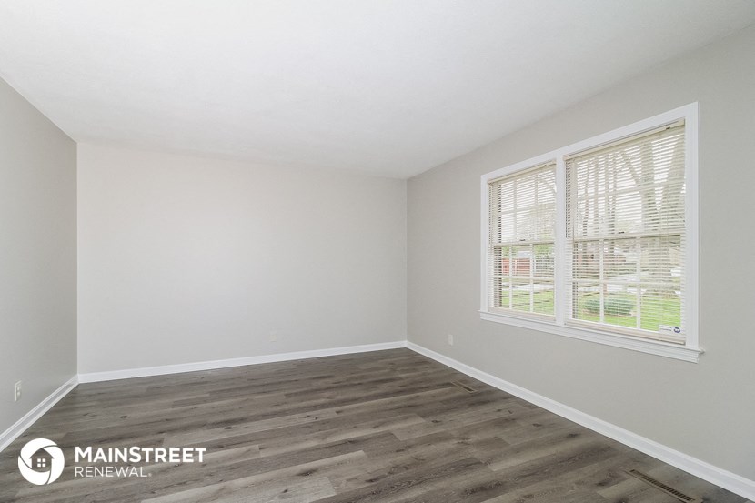 the spacious living room with wood flooring and a large window