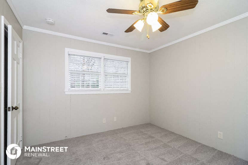 an empty room with a ceiling fan and a window
