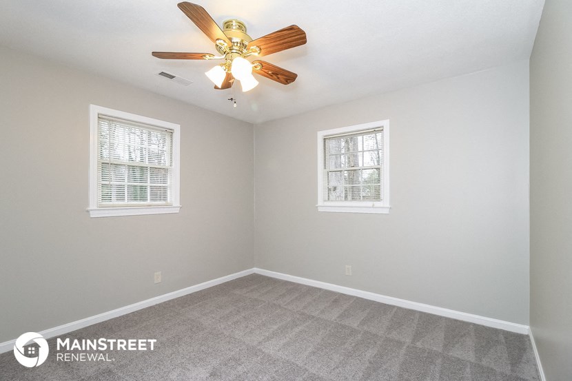 the living room of a home with a ceiling fan and two windows