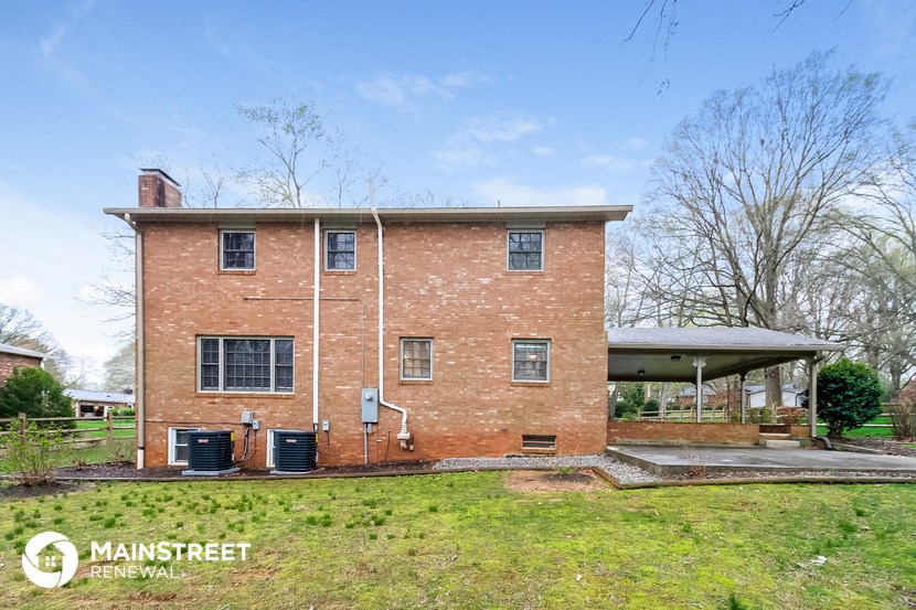 an old brick house with a porch and a grassy yard