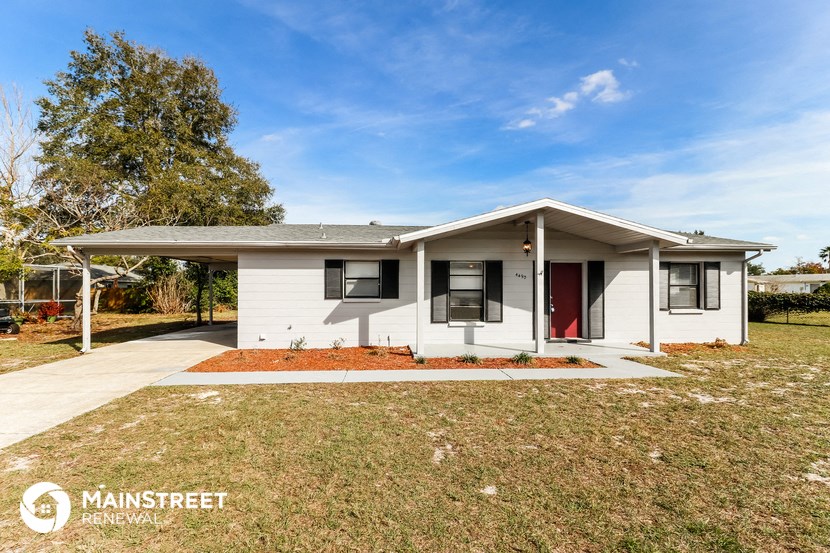 a small white house with a yard and a red door