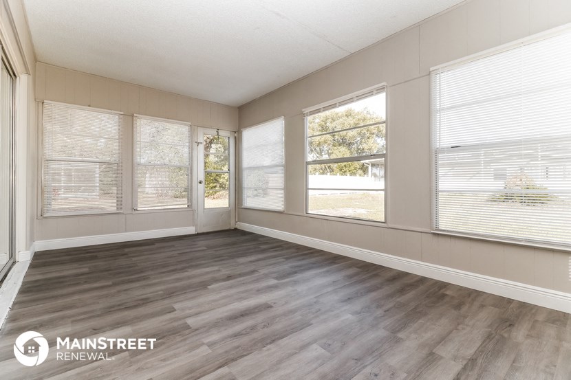 an empty living room with wood floors and windows