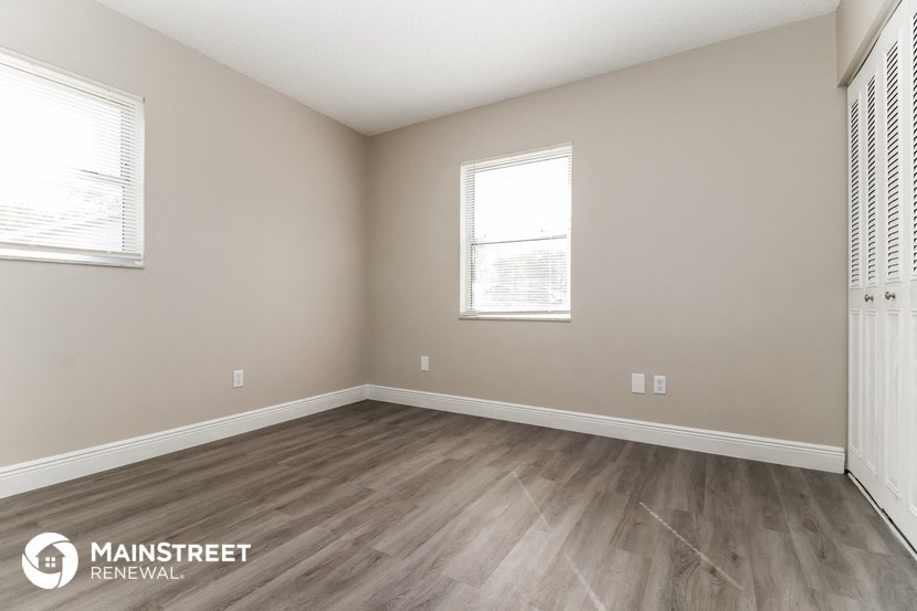 the spacious living room with wood flooring and two windows