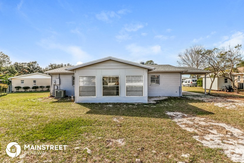 a small white house with a grassy yard and a house behind it