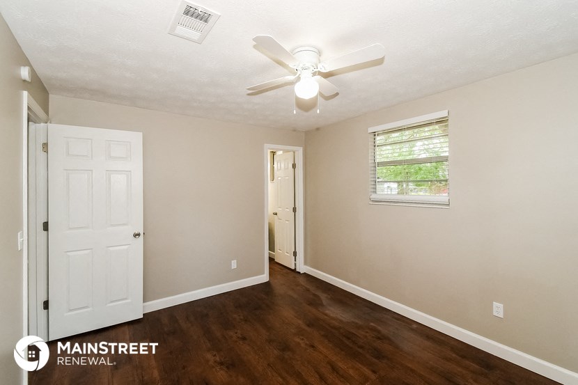 the interior of a renovated home with a ceiling fan and a door