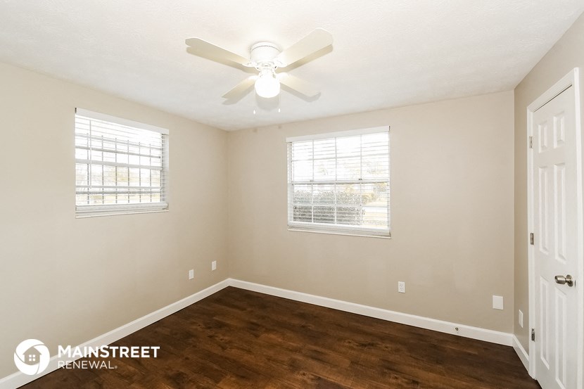 the spacious living room of this manufactured home has a ceiling fan and wood flooring