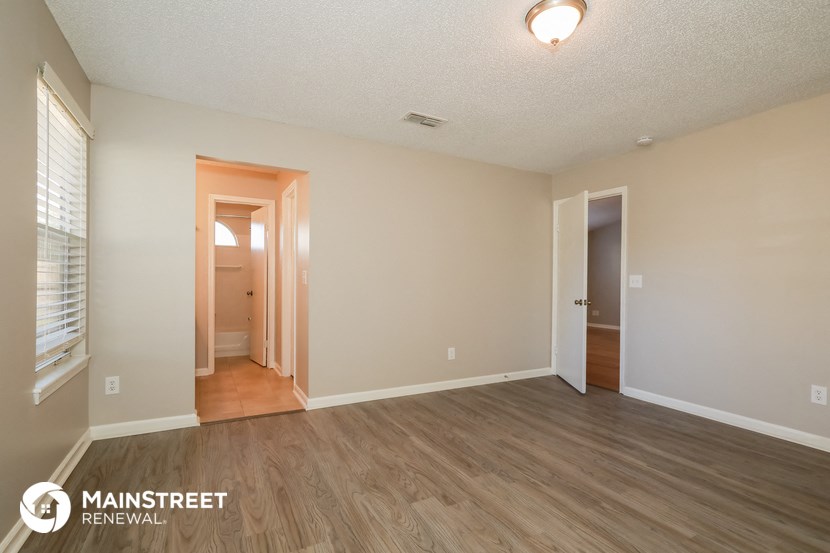 the spacious living room with wood flooring and white walls