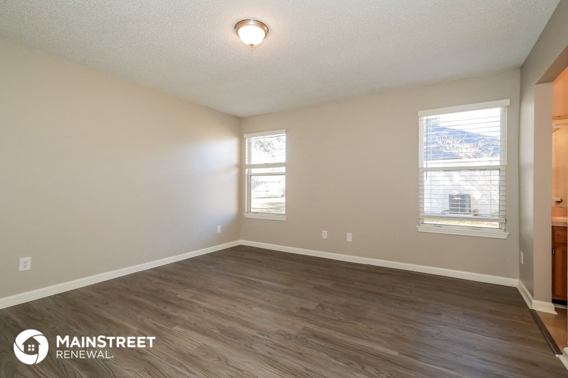 the spacious living room with hardwood flooring and a window