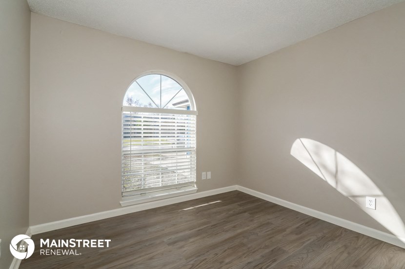 an empty living room with a large window and wood flooring