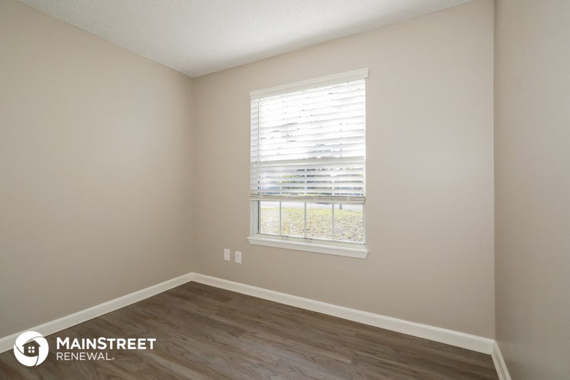 the interior of an empty room with wood floors and a window