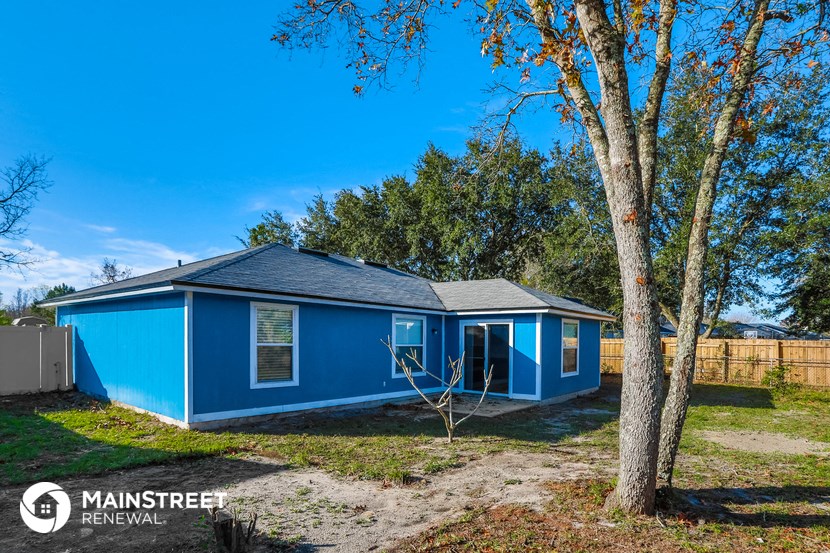 the exterior of a small blue house with a yard and trees