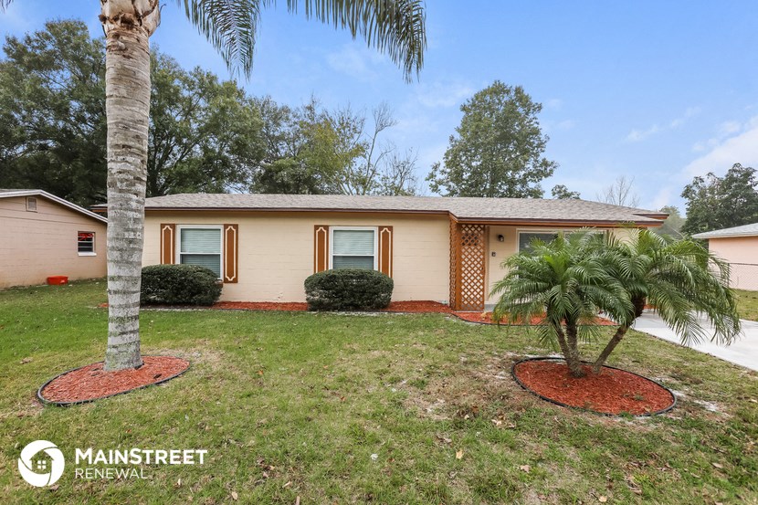 a small tan house with a palm tree in the yard