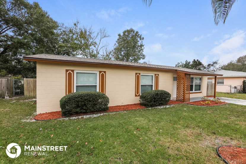 a small tan house with a yard and a lawn