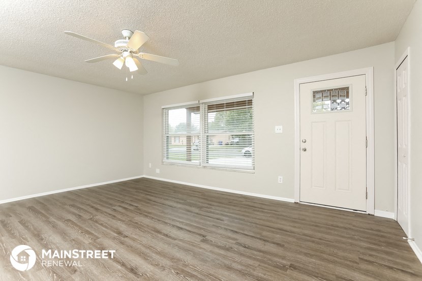 the living room of this home has a large window and a ceiling fan