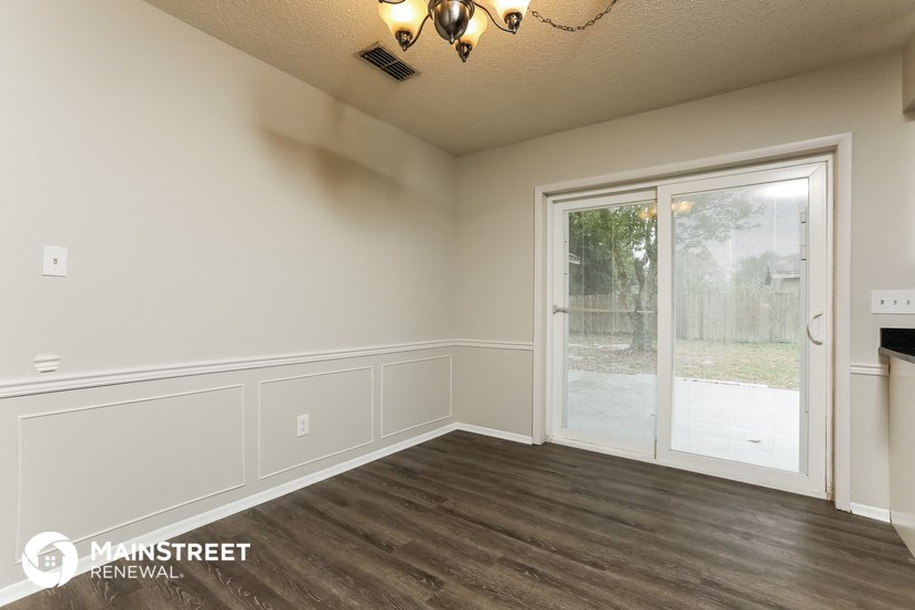 the living room of a home with wood flooring and a sliding glass door